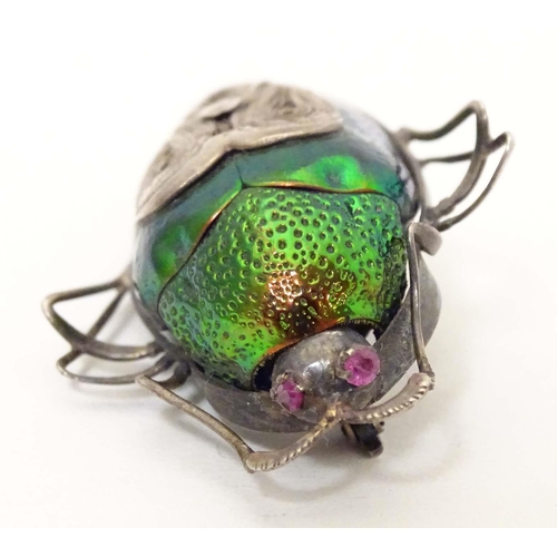 655 - A beetle brooch with white metal mounts, red stone eyes and filigree detail. 2 1/4