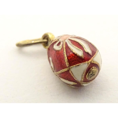 663 - A Russian silver gilt pendant / charm of egg form with red and white enamel detail. Approx. 3/4