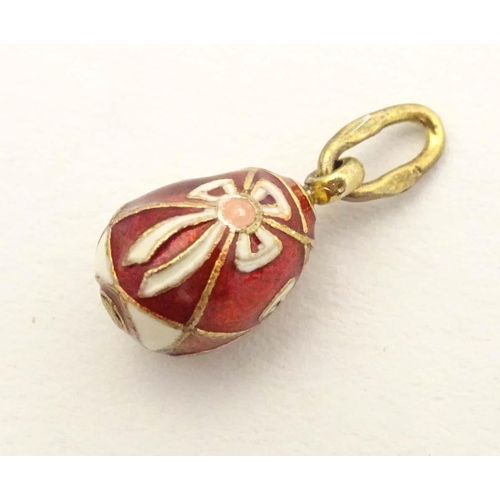 663 - A Russian silver gilt pendant / charm of egg form with red and white enamel detail. Approx. 3/4