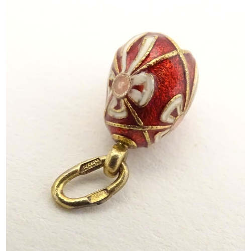 663 - A Russian silver gilt pendant / charm of egg form with red and white enamel detail. Approx. 3/4