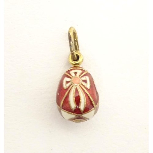 663 - A Russian silver gilt pendant / charm of egg form with red and white enamel detail. Approx. 3/4