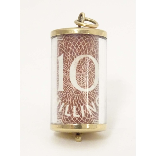 672 - A 9ct gold novelty pendant / charm of cylindrical form with rolled 10 shilling note to centre. Appro... 