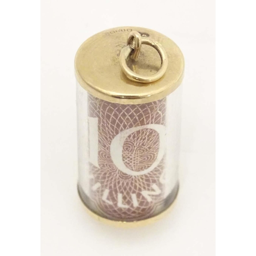 672 - A 9ct gold novelty pendant / charm of cylindrical form with rolled 10 shilling note to centre. Appro... 