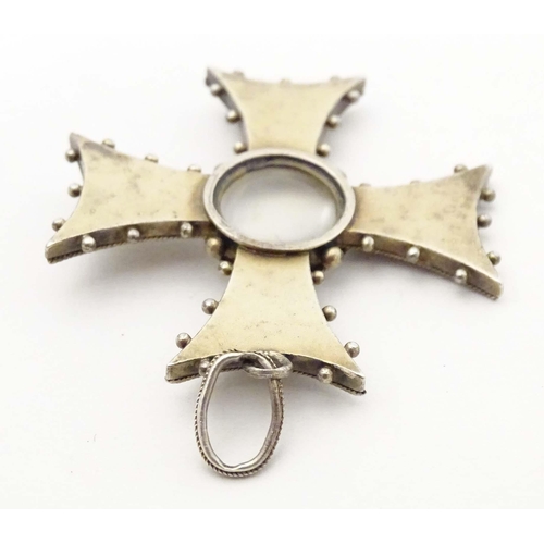 673 - A white metal pendant of cross form with scroll detail, set with central moonstone cabochon. Approx.... 