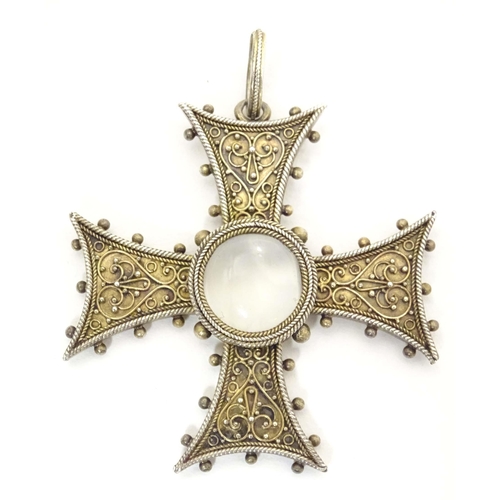 673 - A white metal pendant of cross form with scroll detail, set with central moonstone cabochon. Approx.... 