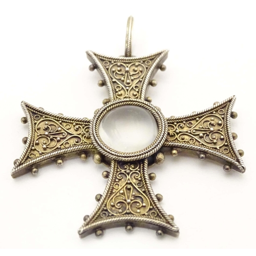 673 - A white metal pendant of cross form with scroll detail, set with central moonstone cabochon. Approx.... 