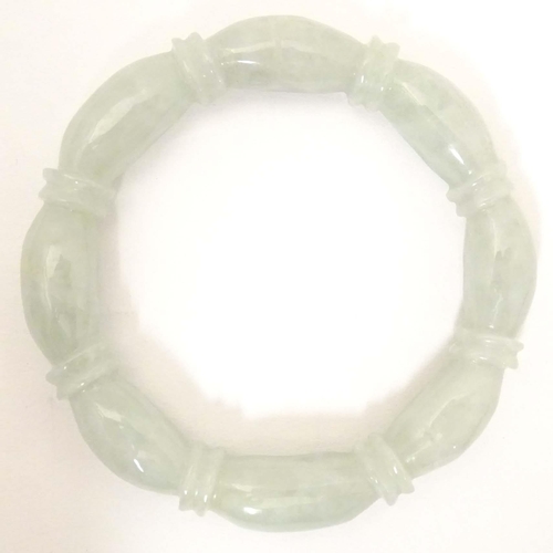 675 - A green jade bracelet of bangle form with carved detail.