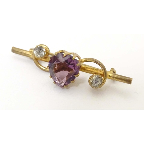 680 - A gilt metal bar brooch set with central amethyst coloured heart shaped stone to centre flanked by t... 