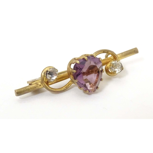 680 - A gilt metal bar brooch set with central amethyst coloured heart shaped stone to centre flanked by t... 