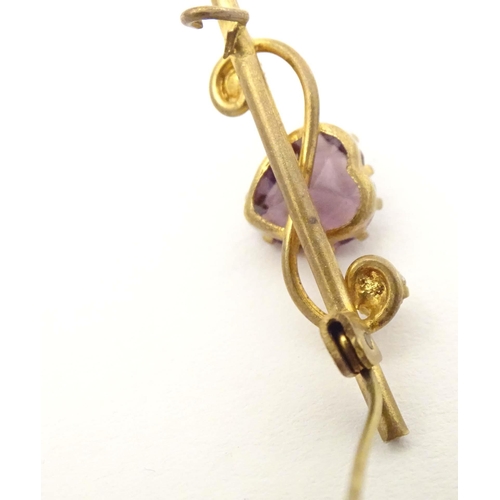 680 - A gilt metal bar brooch set with central amethyst coloured heart shaped stone to centre flanked by t... 