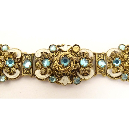 683 - A gilt metal bracelet with filigree and enamel detail and set with green paste stones. Approx. 7 3/4... 