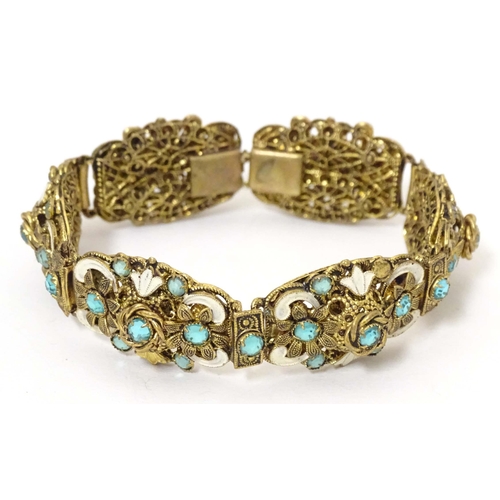 683 - A gilt metal bracelet with filigree and enamel detail and set with green paste stones. Approx. 7 3/4... 