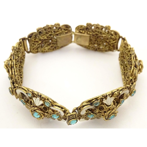 683 - A gilt metal bracelet with filigree and enamel detail and set with green paste stones. Approx. 7 3/4... 