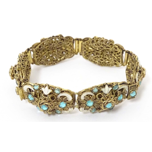 683 - A gilt metal bracelet with filigree and enamel detail and set with green paste stones. Approx. 7 3/4... 