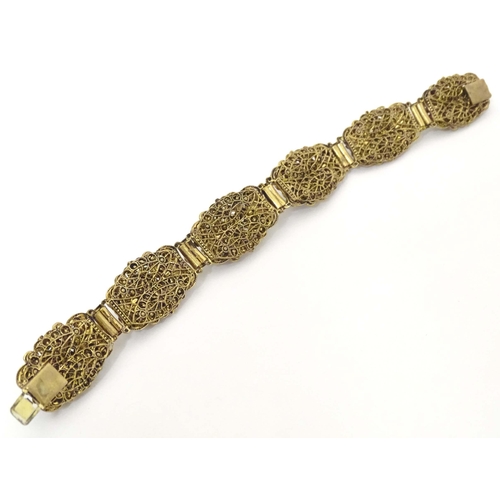 683 - A gilt metal bracelet with filigree and enamel detail and set with green paste stones. Approx. 7 3/4... 