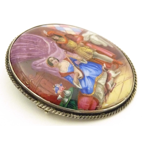 686 - An oval brooch with enamel scene to centre depicting a couple with their dog, within a white metal m... 