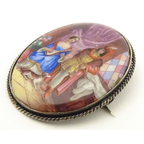 686 - An oval brooch with enamel scene to centre depicting a couple with their dog, within a white metal m... 