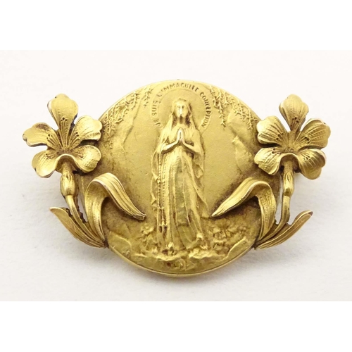 690 - An early 20thC Continental gilt metal brooch depicting the Virgin Mary to centre flanked by floral d... 