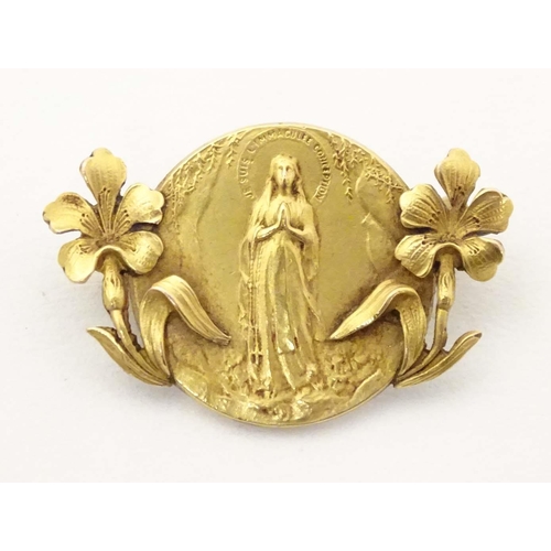 690 - An early 20thC Continental gilt metal brooch depicting the Virgin Mary to centre flanked by floral d... 