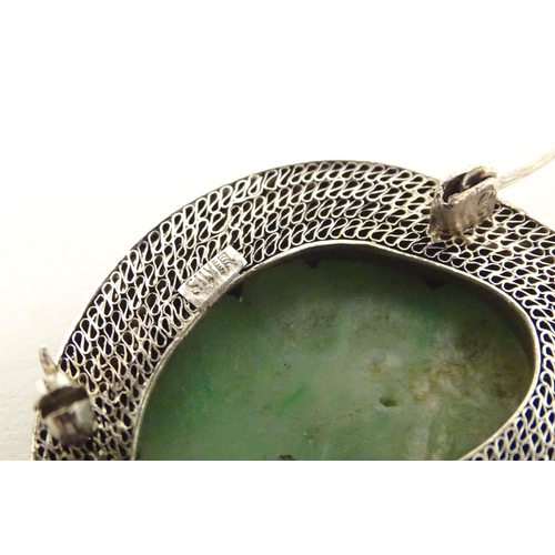 695 - An Oriental brooch with carved jade detail within a silver mount. Approx. 1 3/4