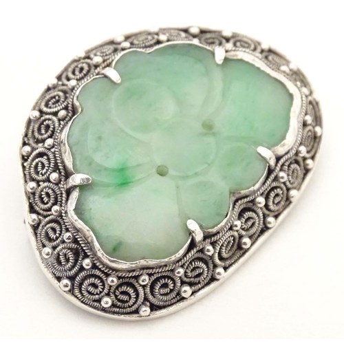 695 - An Oriental brooch with carved jade detail within a silver mount. Approx. 1 3/4