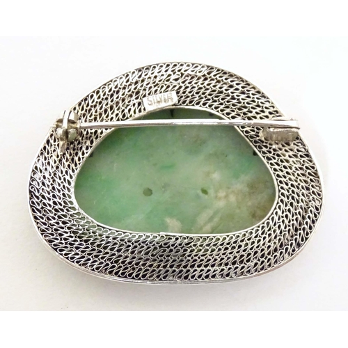 695 - An Oriental brooch with carved jade detail within a silver mount. Approx. 1 3/4