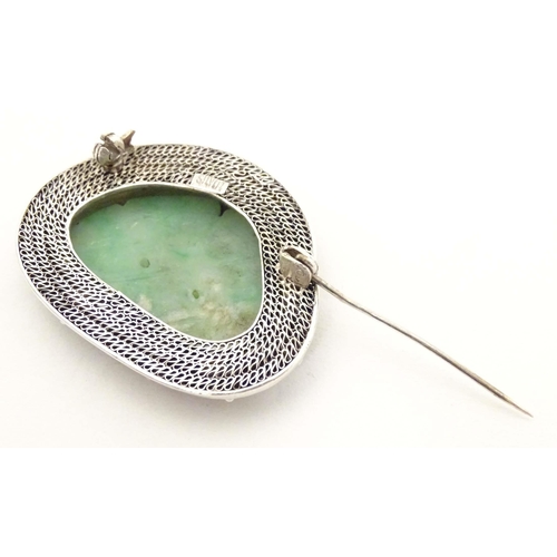 695 - An Oriental brooch with carved jade detail within a silver mount. Approx. 1 3/4