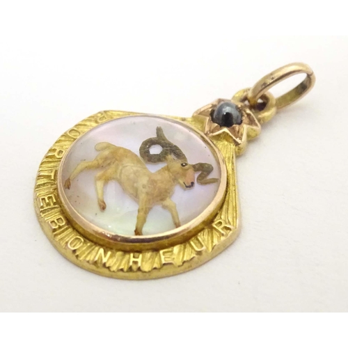 696 - A c.1900 French gold pendant / lucky charm set with Essex crystal style cabochon to centre depicting... 