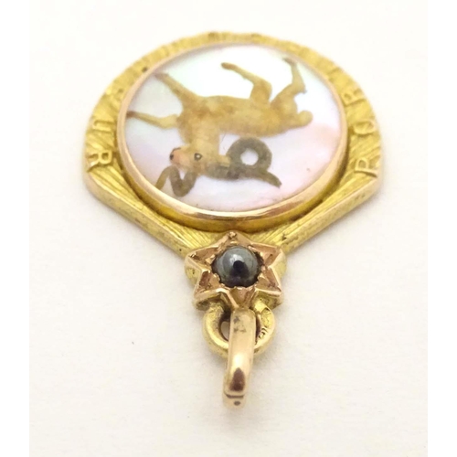 696 - A c.1900 French gold pendant / lucky charm set with Essex crystal style cabochon to centre depicting... 