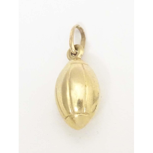 698 - A 9ct gold and gilt metal novelty pendant / charm formed as a rugby ball. Approx. 1