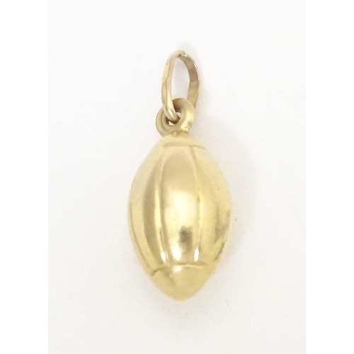 698 - A 9ct gold and gilt metal novelty pendant / charm formed as a rugby ball. Approx. 1