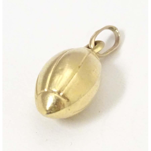 698 - A 9ct gold and gilt metal novelty pendant / charm formed as a rugby ball. Approx. 1