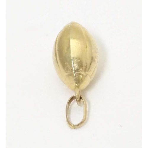 698 - A 9ct gold and gilt metal novelty pendant / charm formed as a rugby ball. Approx. 1