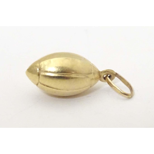 698 - A 9ct gold and gilt metal novelty pendant / charm formed as a rugby ball. Approx. 1