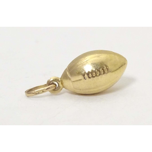 698 - A 9ct gold and gilt metal novelty pendant / charm formed as a rugby ball. Approx. 1