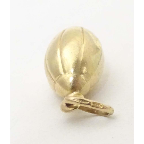 698 - A 9ct gold and gilt metal novelty pendant / charm formed as a rugby ball. Approx. 1