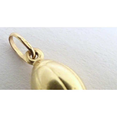 698 - A 9ct gold and gilt metal novelty pendant / charm formed as a rugby ball. Approx. 1