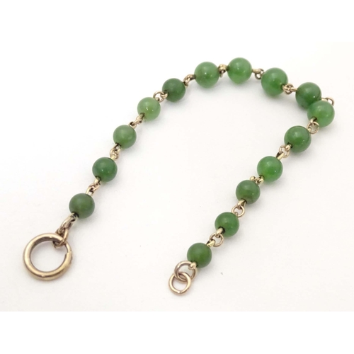 700 - A bracelet of green jade beads with yellow metal links and clasp. Approx. 7 1/2