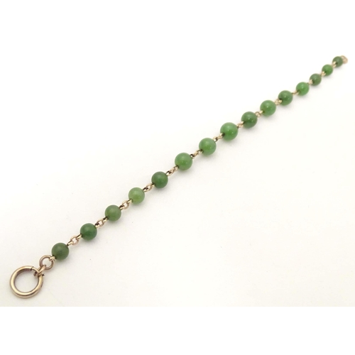 700 - A bracelet of green jade beads with yellow metal links and clasp. Approx. 7 1/2