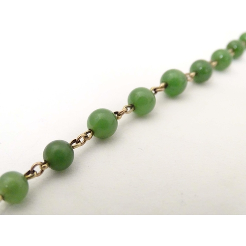 700 - A bracelet of green jade beads with yellow metal links and clasp. Approx. 7 1/2