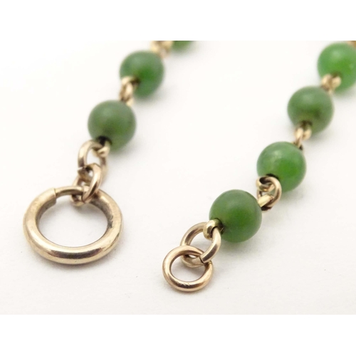 700 - A bracelet of green jade beads with yellow metal links and clasp. Approx. 7 1/2