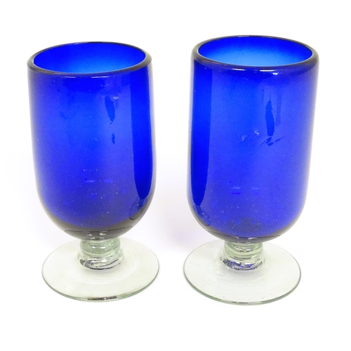 283 - Two Bristol blue style pedestal vases / glasses on a clear glass foot. The tallest approx 6 1/2