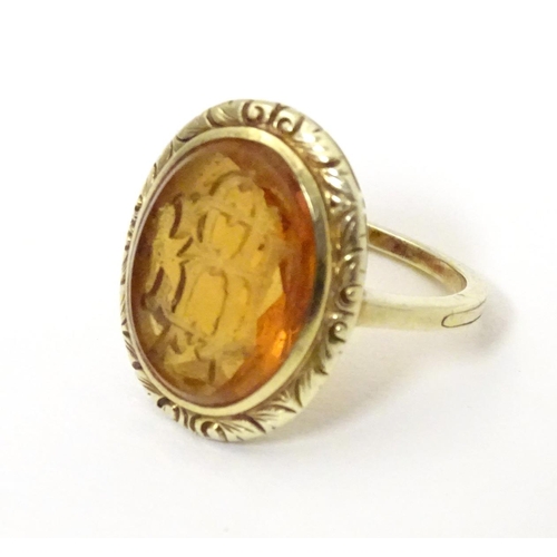 567 - A late 19th / early 20thC yellow metal ring with engraved citrine seal to top depicting monogram. Ri... 