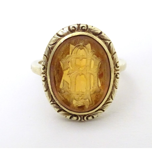 567 - A late 19th / early 20thC yellow metal ring with engraved citrine seal to top depicting monogram. Ri... 