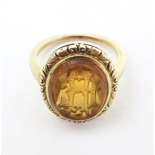 567 - A late 19th / early 20thC yellow metal ring with engraved citrine seal to top depicting monogram. Ri... 