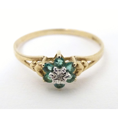 571 - A 9ct gold ring set with central diamond bordered by emeralds. Ring size approx. S 1/2