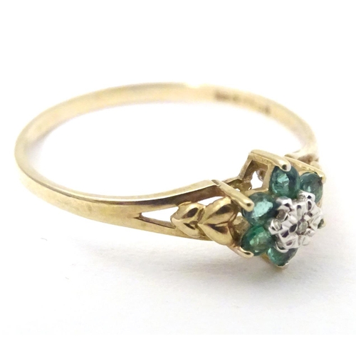 571 - A 9ct gold ring set with central diamond bordered by emeralds. Ring size approx. S 1/2