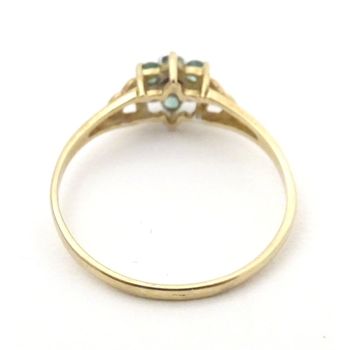 571 - A 9ct gold ring set with central diamond bordered by emeralds. Ring size approx. S 1/2