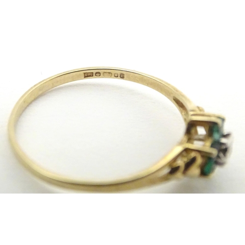 571 - A 9ct gold ring set with central diamond bordered by emeralds. Ring size approx. S 1/2