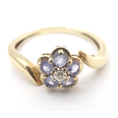 572 - A 9ct gold ring set with central diamond bordered by five tanzanite stones. Ring size approx. N 1/2